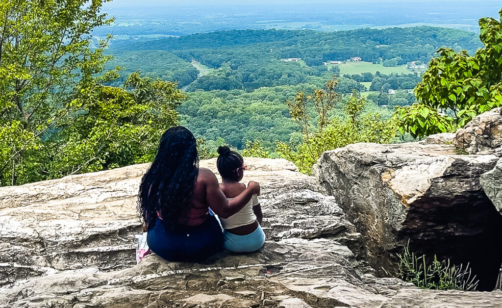 mom and child sitting on overlook hiking