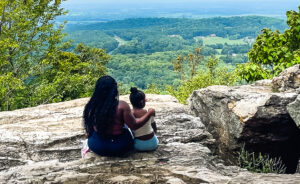 mom and child sitting on overlook hiking
